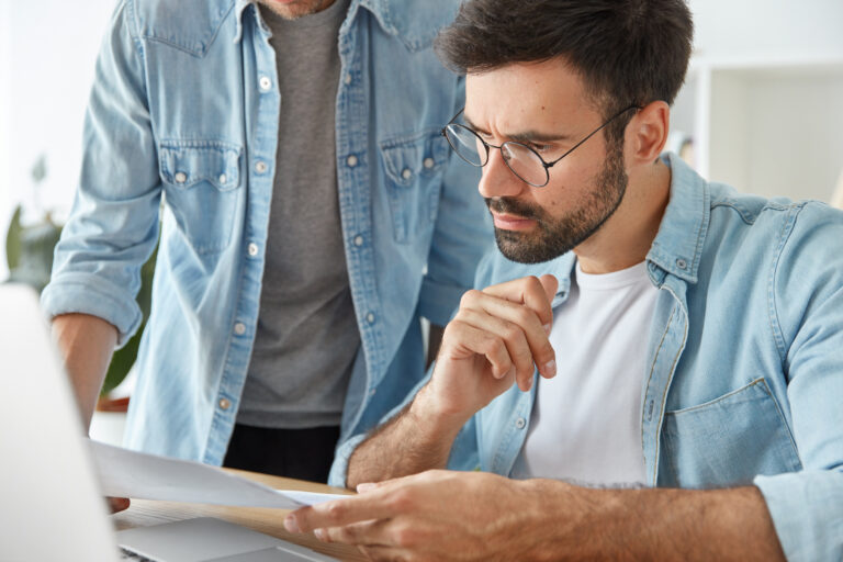 Male project managers analyse project or new startup, collaborate together, sit in modern office. Pe